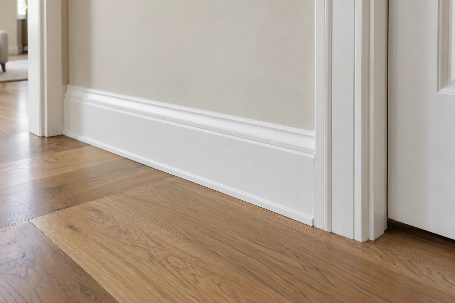White baseboard trim along a light wall beside a doorway, above a warm wood floor.